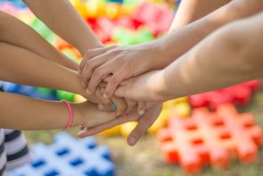 Viele Kinderhände übereinanderliegend als Symbol des Zusammenhalts