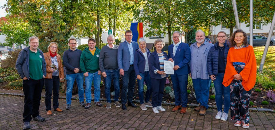 Der Kreisbeigeordnete übergibt den Förderbescheid an die Bürgermeisterin, drumherum weitere Beteiligte